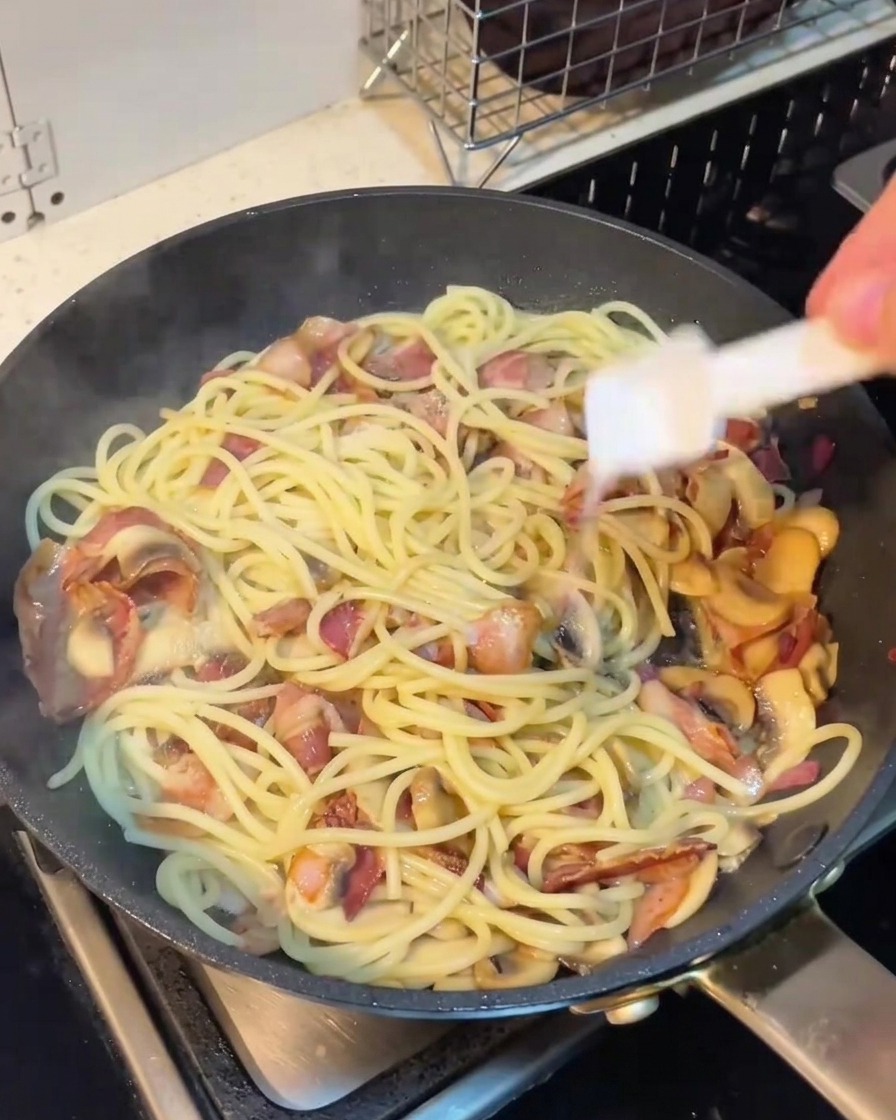 팬 위의 파스타에 소금과 후추를 뿌리는 모습.
