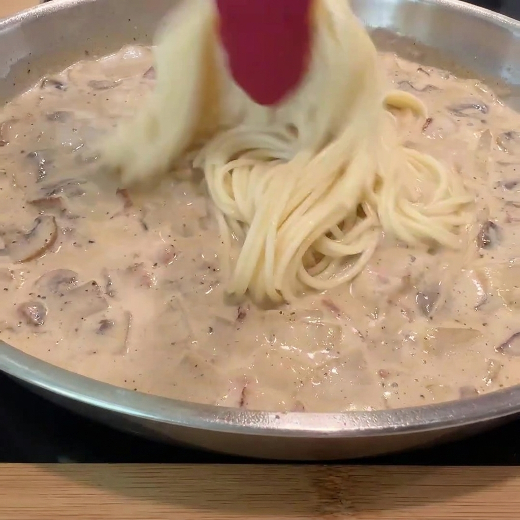 삶아진 스파게티 면을 소스 팬으로 옮겨 담는 모습.