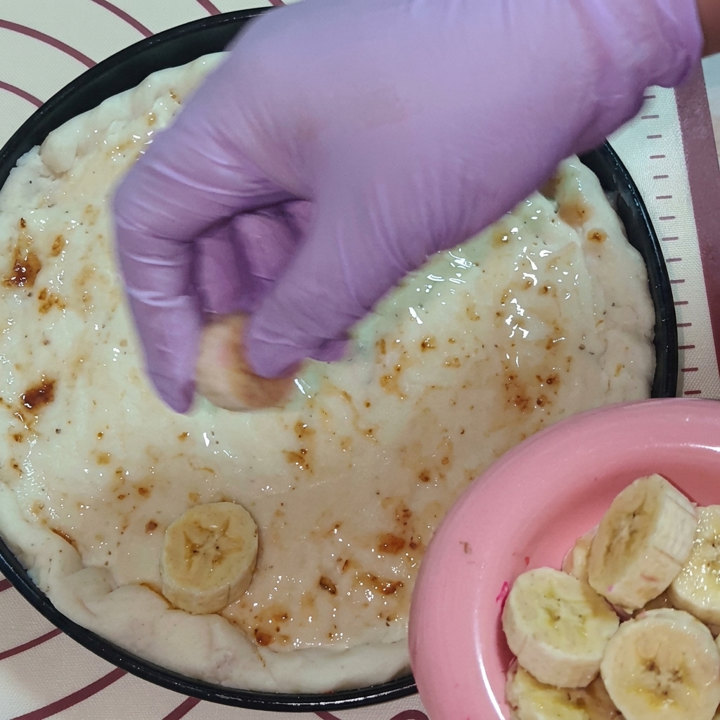 장갑을 낀 손으로 슬라이스한 바나나와 용과를 토핑하는 모습.