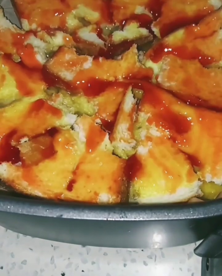 토마토 소스를 바른 식빵 위에 옥수수와 완두콩 등 알록달록한 혼합 채소를 뿌리는 모습.