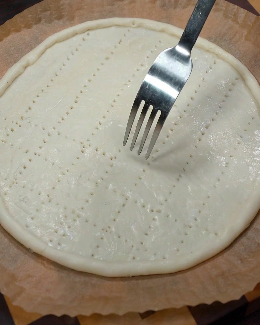 포크로 파전 중앙에 여러 개의 구멍을 내고 있는 모습.
