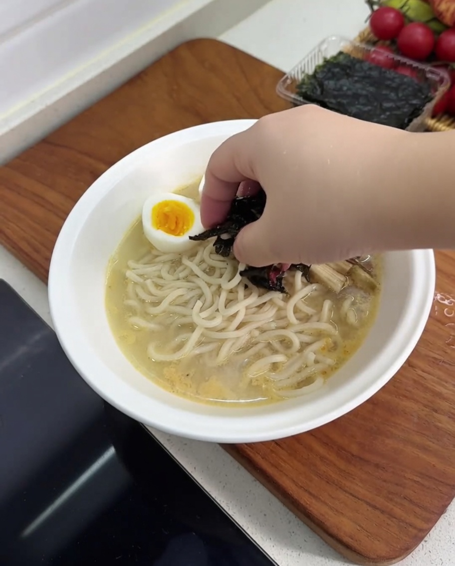 반으로 자른 삶은 달걀, 버섯, 죽순, 김으로 고명이 올라간 라면 그릇.