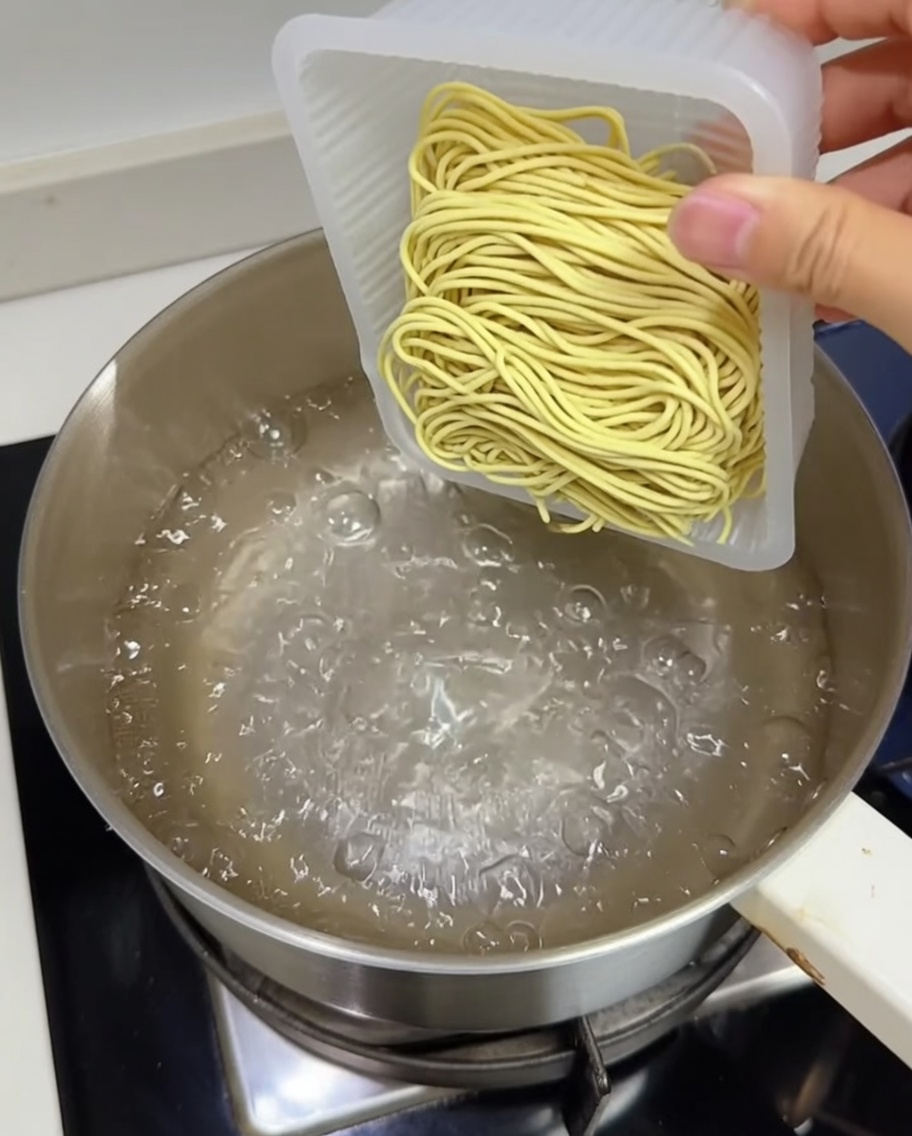 끓는 물이 담긴 냄비에 신선한 생면 덩어리를 넣는 모습.
