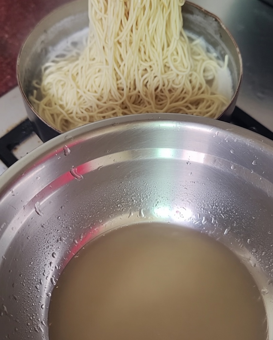 삶아진 면을 젓가락으로 건지는 모습.