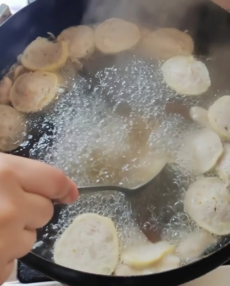 완자와 목이버섯이 든 육수에 양념을 넣고 젓는 모습.