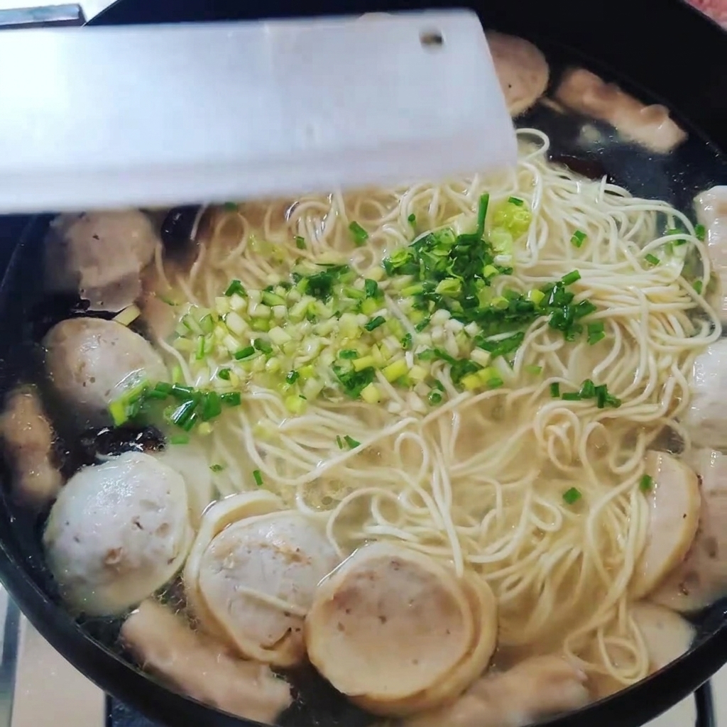 면과 완자 위에 다진 대파를 올리는 모습.