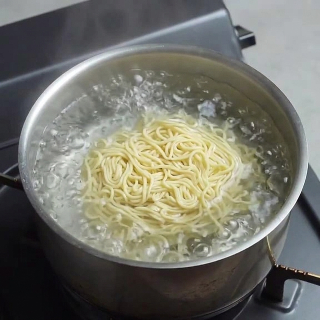 끓는 물에 노란 생라멘 면을 삶는 모습