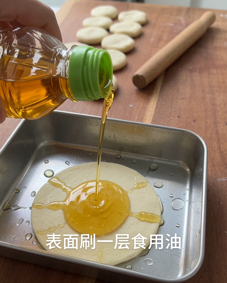 금속 용기에 담긴 반죽 조각 위에 식용유를 뿌리는 모습.