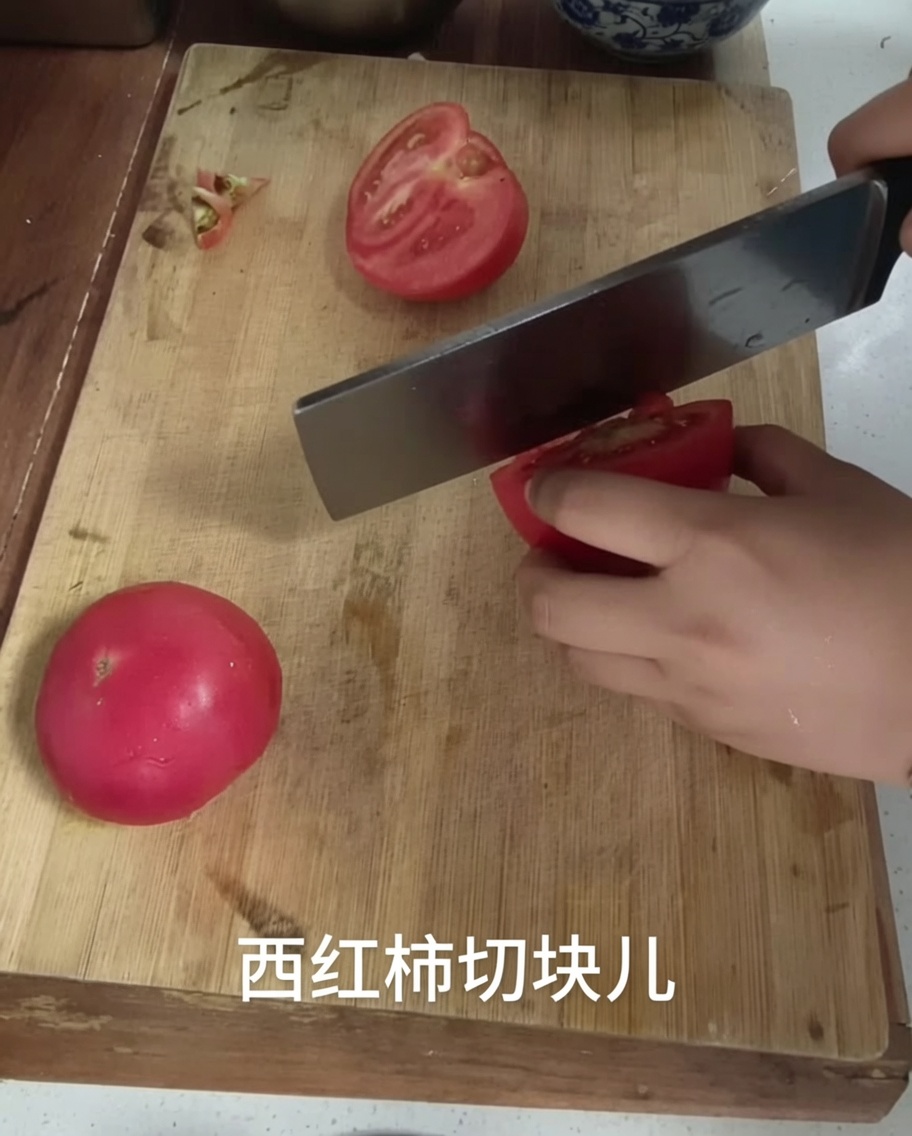 나무 도마 위에서 칼로 토마토를 깍둑썰기하는 모습.