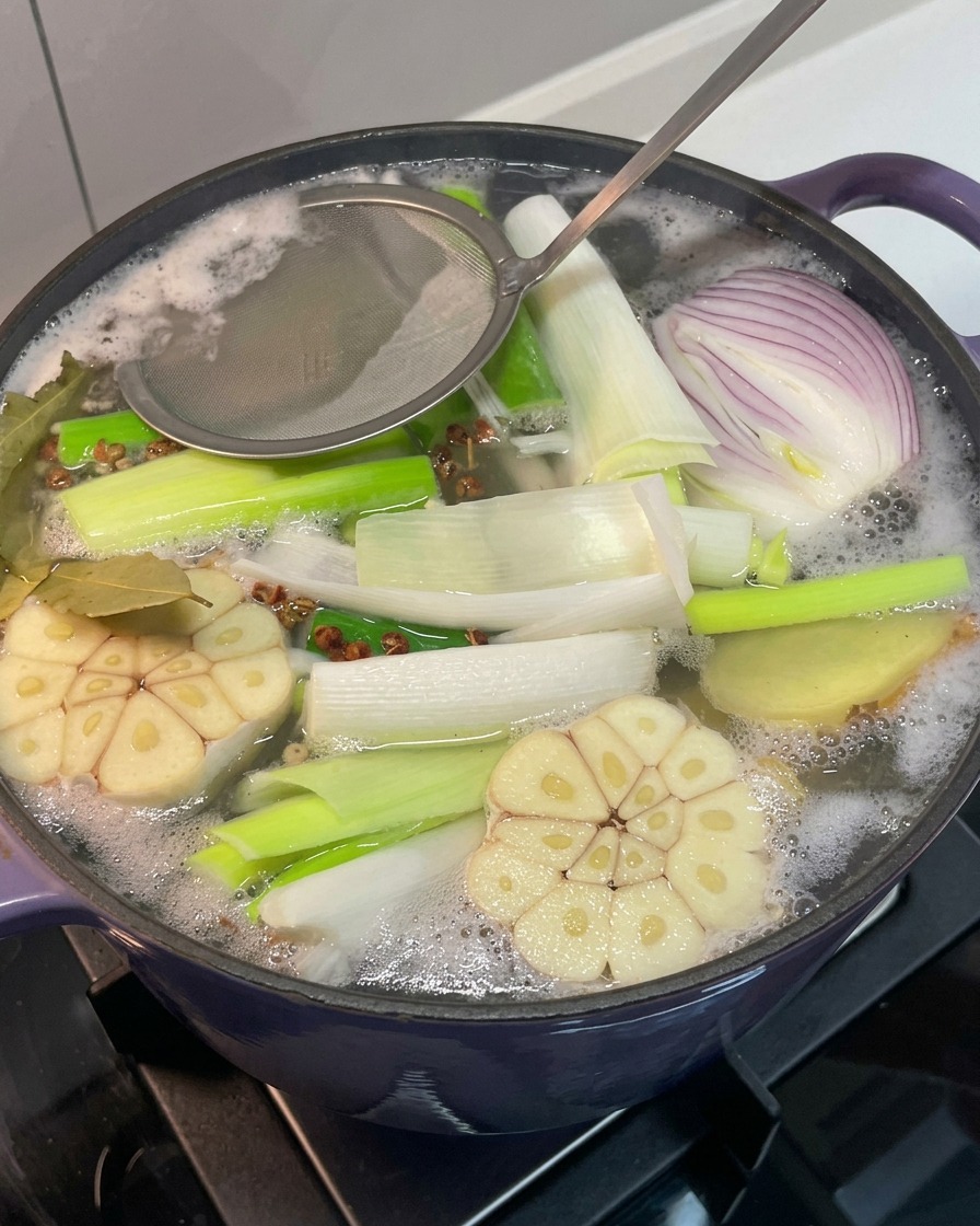 끓어오르는 육수의 불순물과 거품을 체로 걷어내는 모습.