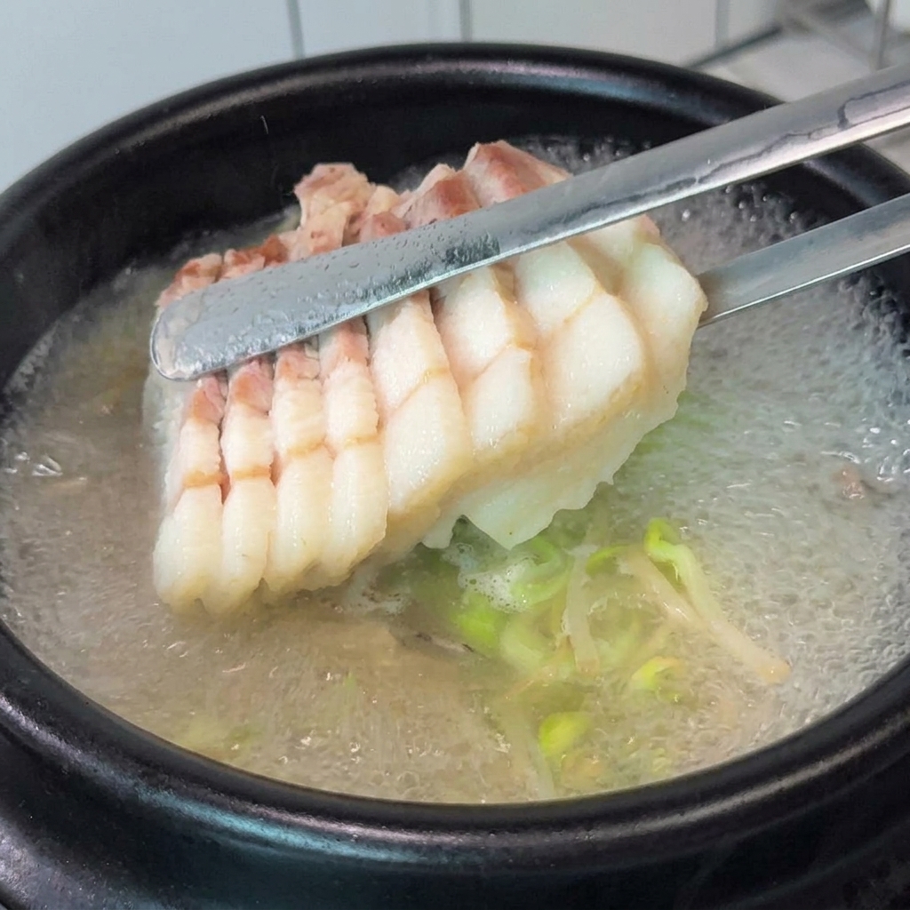 끓는 국밥 위에 수육과 부추를 올리는 모습.