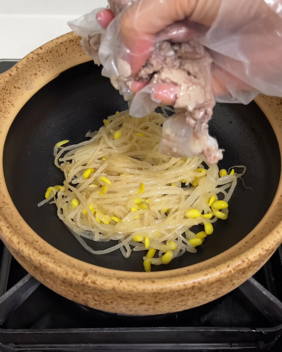 잘 삶아진 돼지 등뼈를 콩나물 위에 올리는 모습.