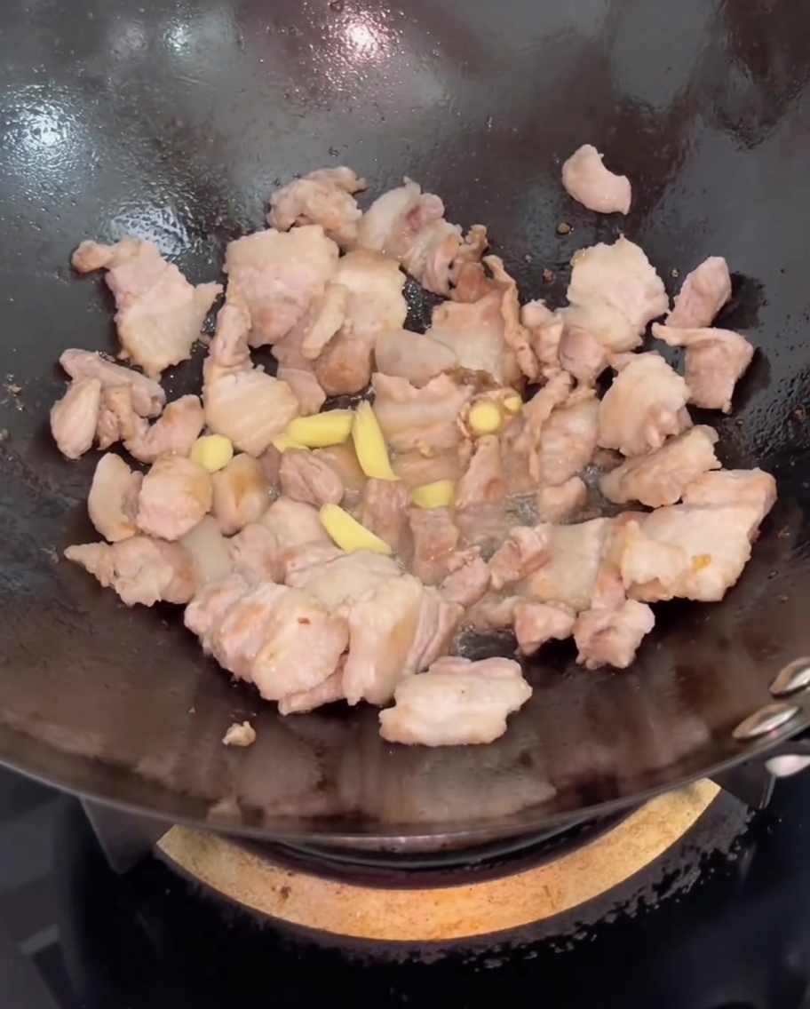 볶아진 삼겹살에 생강 슬라이스를 넣고 섞는 모습.