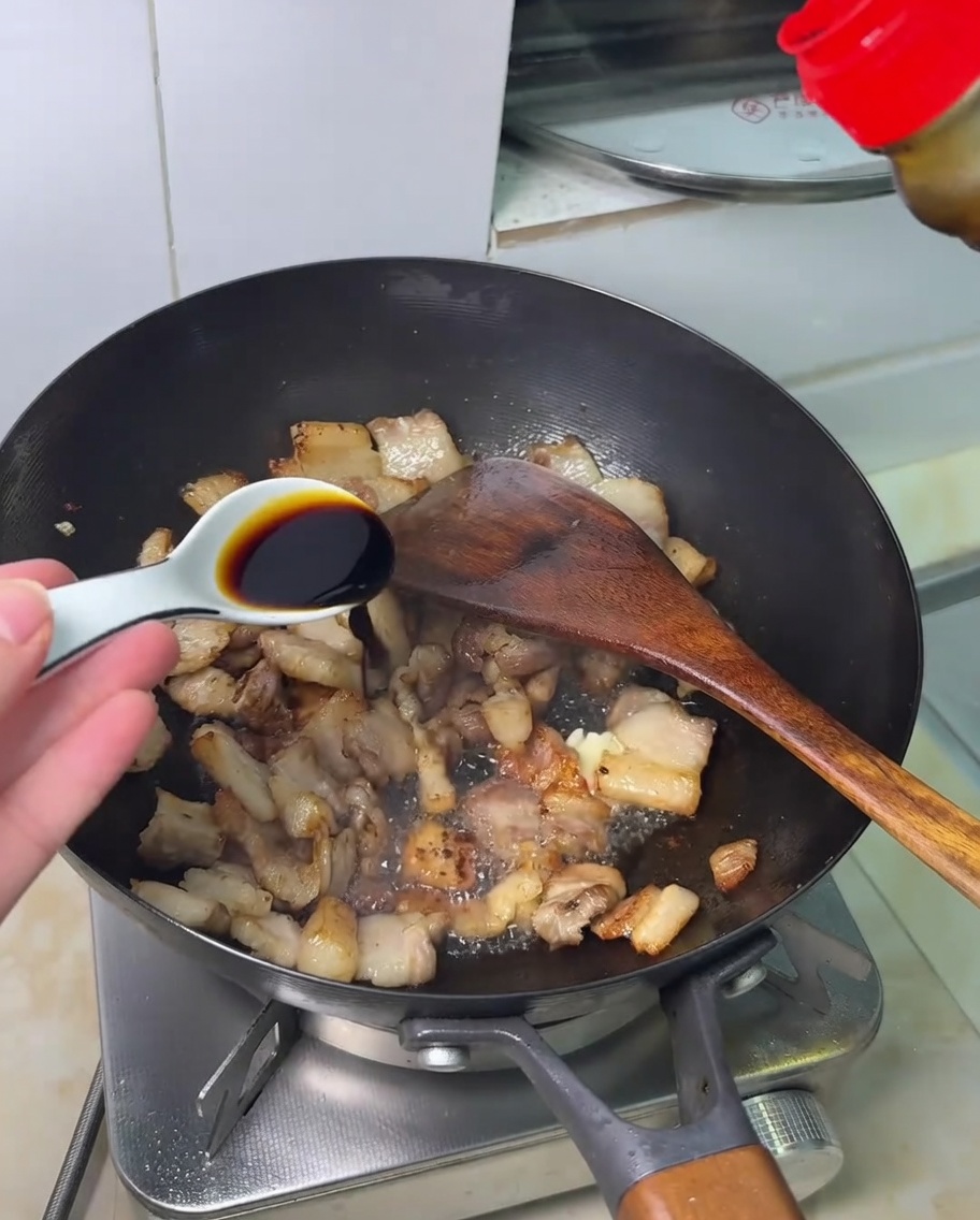 볶아진 삼겹살 위로 간장을 뿌리는 모습.