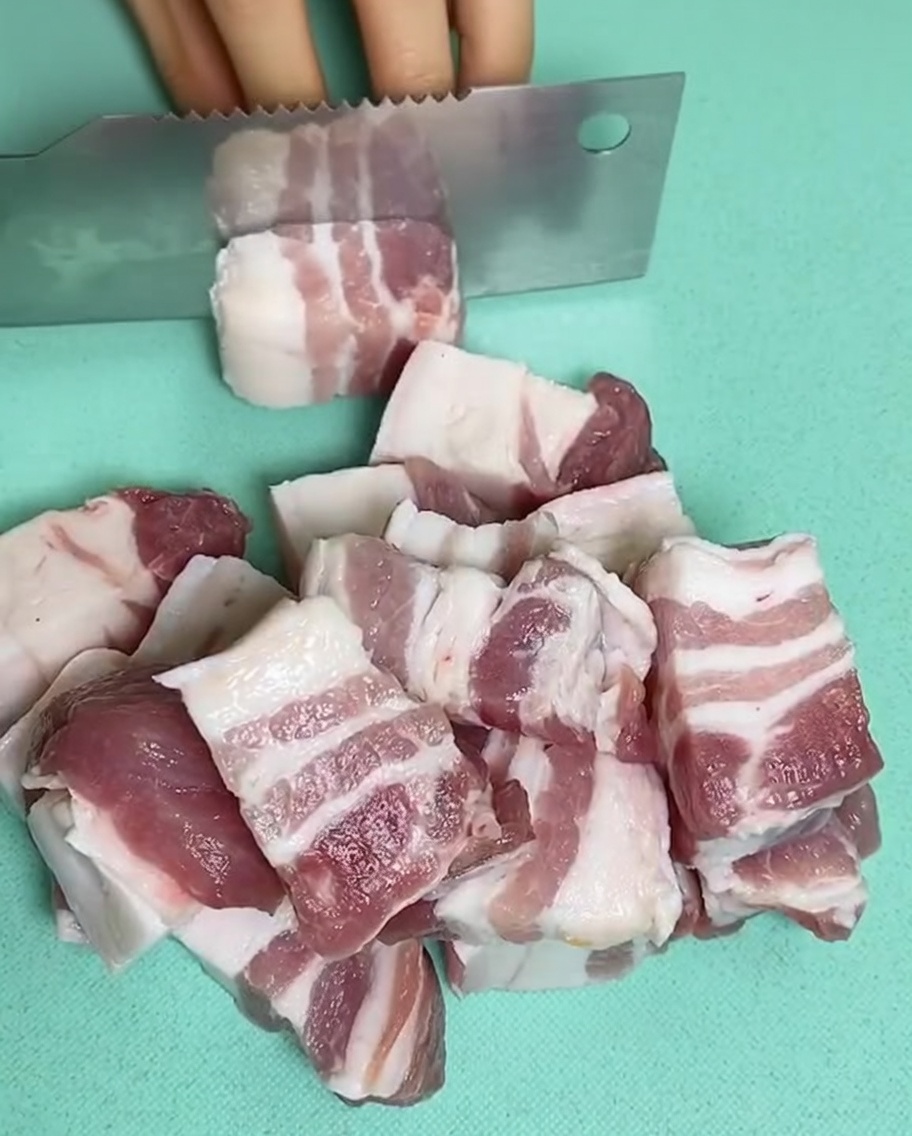 찬물, 생강, 요리용 술이 담긴 냄비에 돼지고기 조각을 넣는 모습.