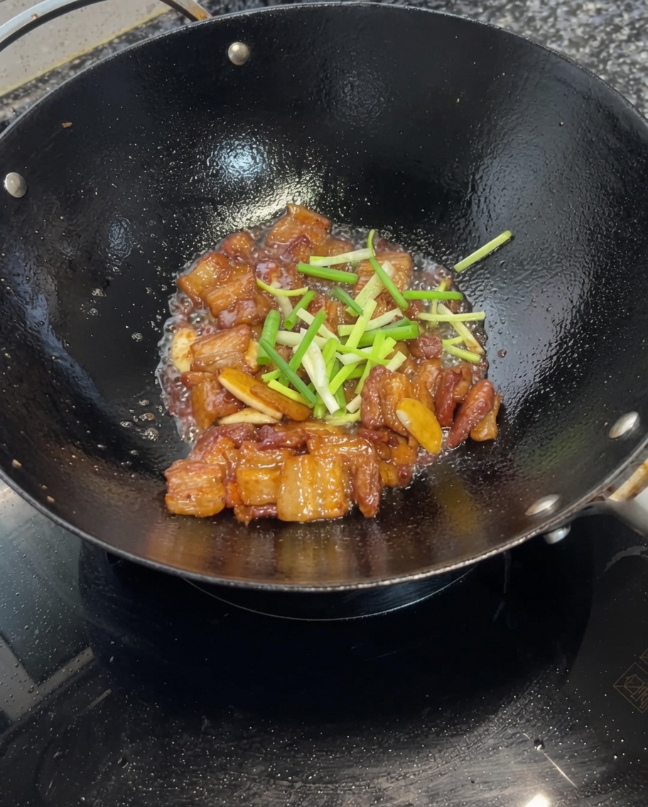 손질한 대파를 넣고 간장 삼겹살과 함께 가볍게 뒤섞는 모습.