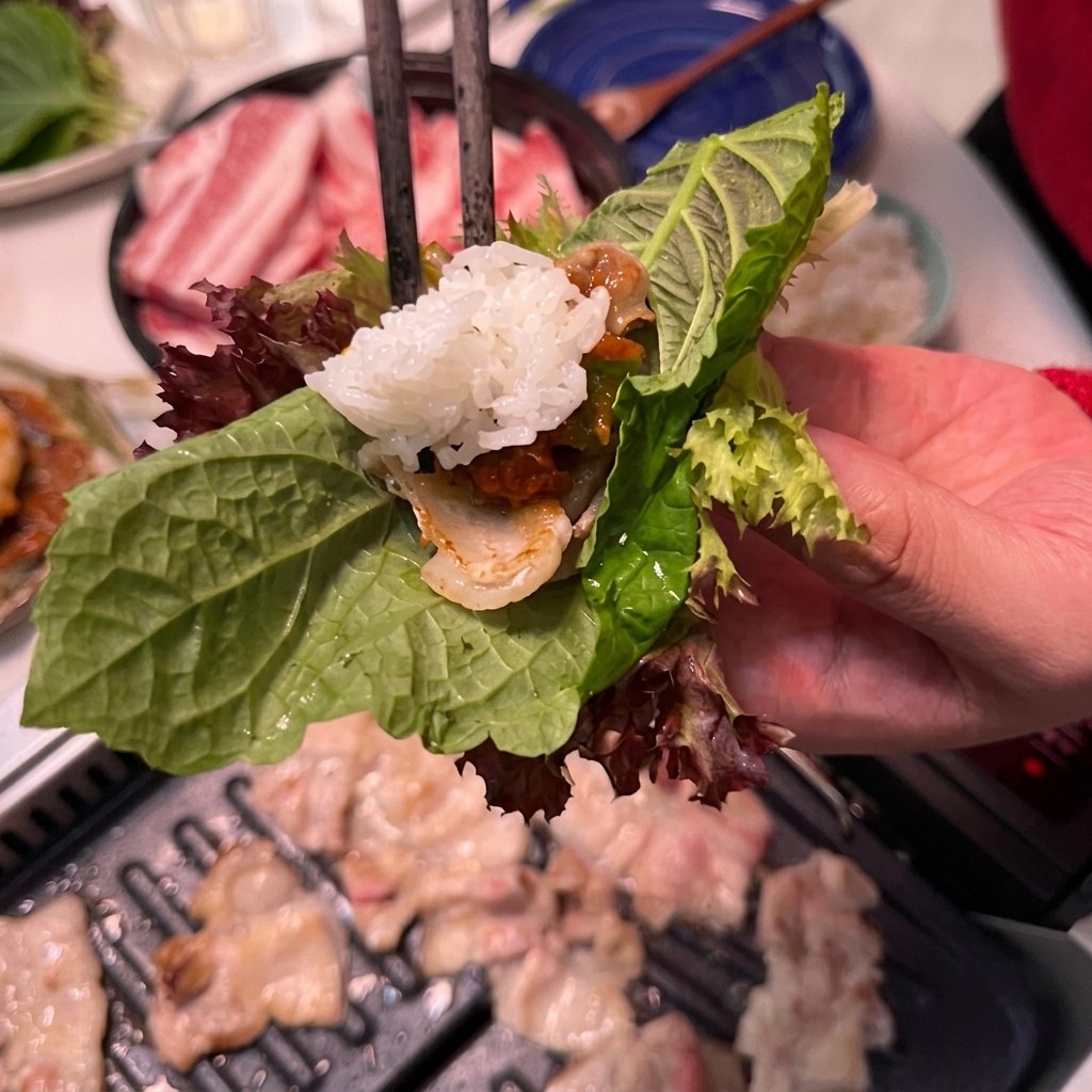 쌈 위에 밥을 한 숟가락 올리는 모습.