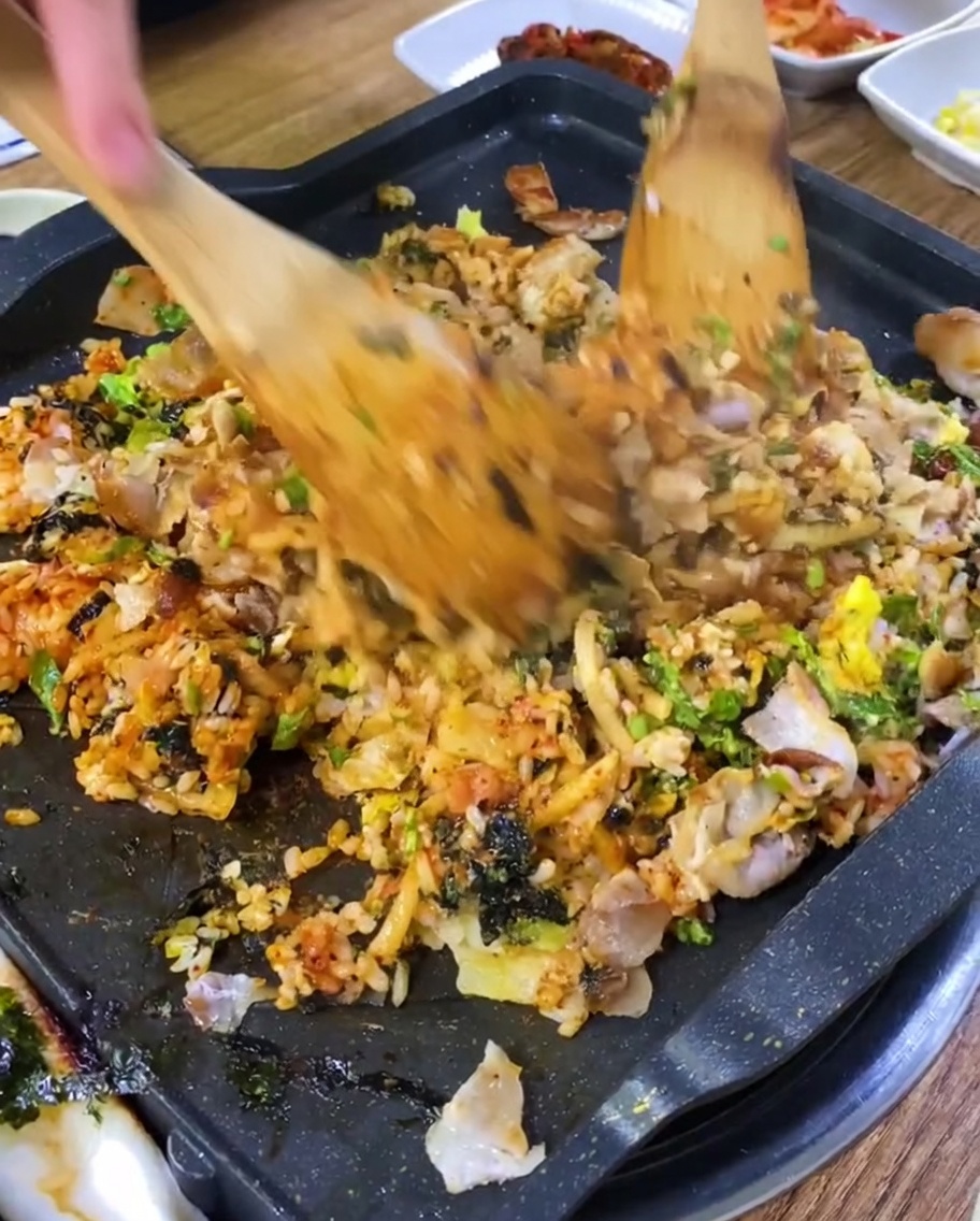 철판 위에서 삼겹살과 밥을 함께 볶는 모습.