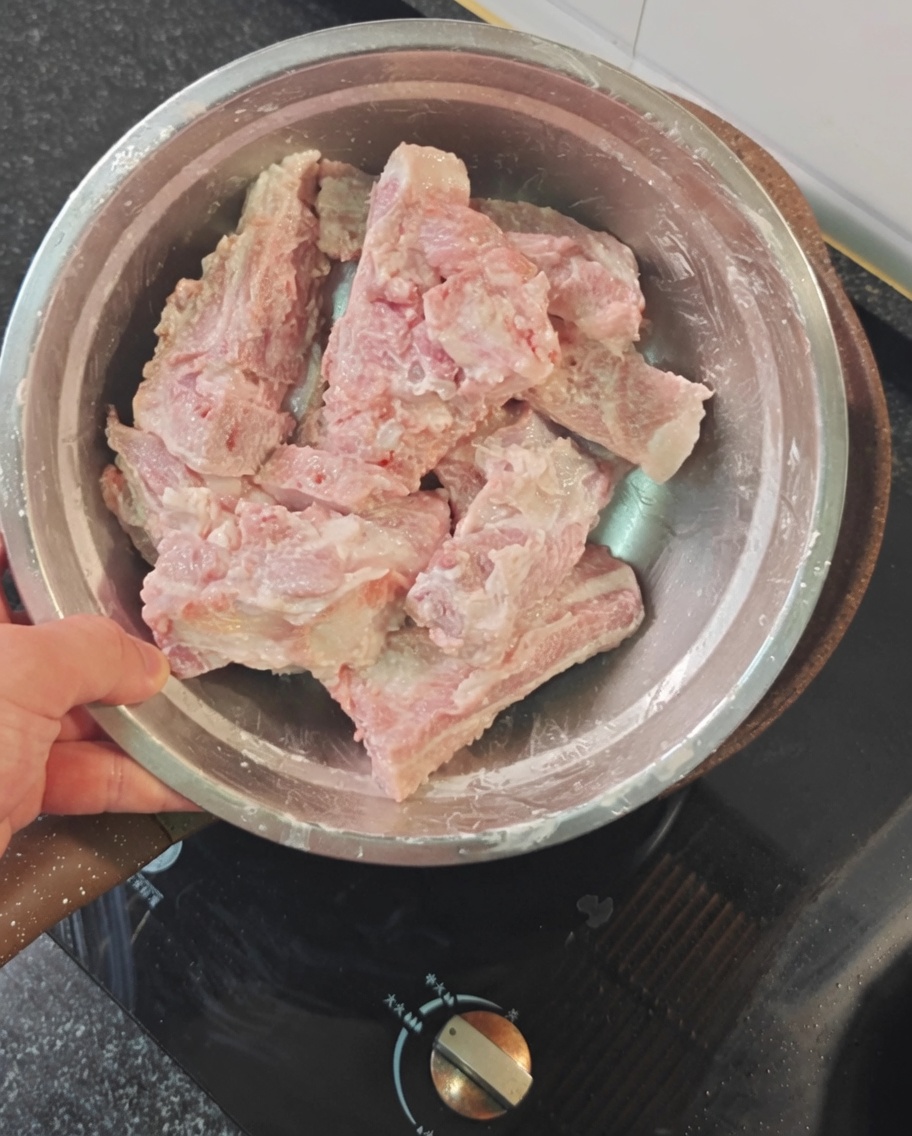 볼에 담긴 돼지갈비에 붉은 전분 가루를 고루 입히는 모습.