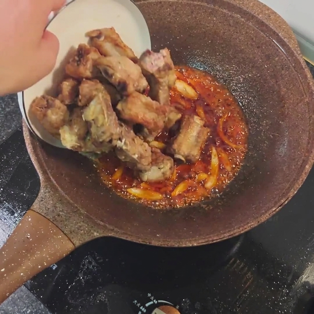 구운 갈비를 소스 팬에 넣고 섞는 모습.