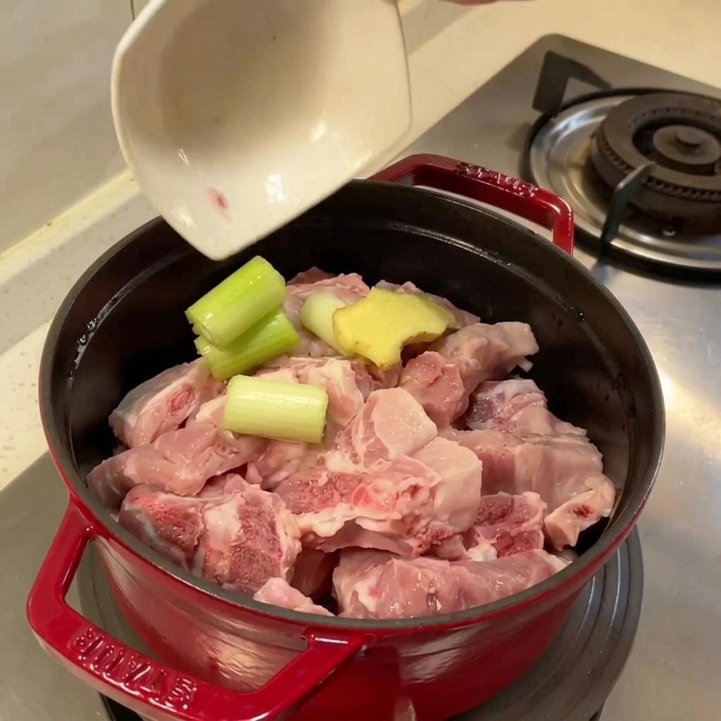 생강과 대파가 함께 들어가 삶을 준비가 된 생 돼지갈비가 담긴 냄비.