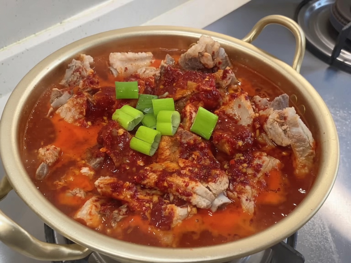 양념된 갈비 위에 신선하게 썬 송송 대파가 얹어지고 있는 냄비.