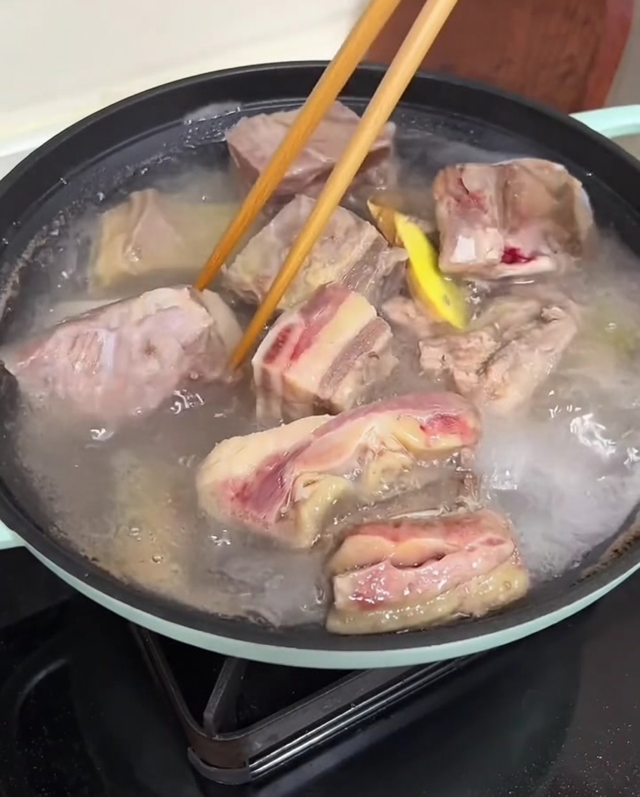 데친 갈비를 흐르는 따뜻한 물에 세척하는 모습.
