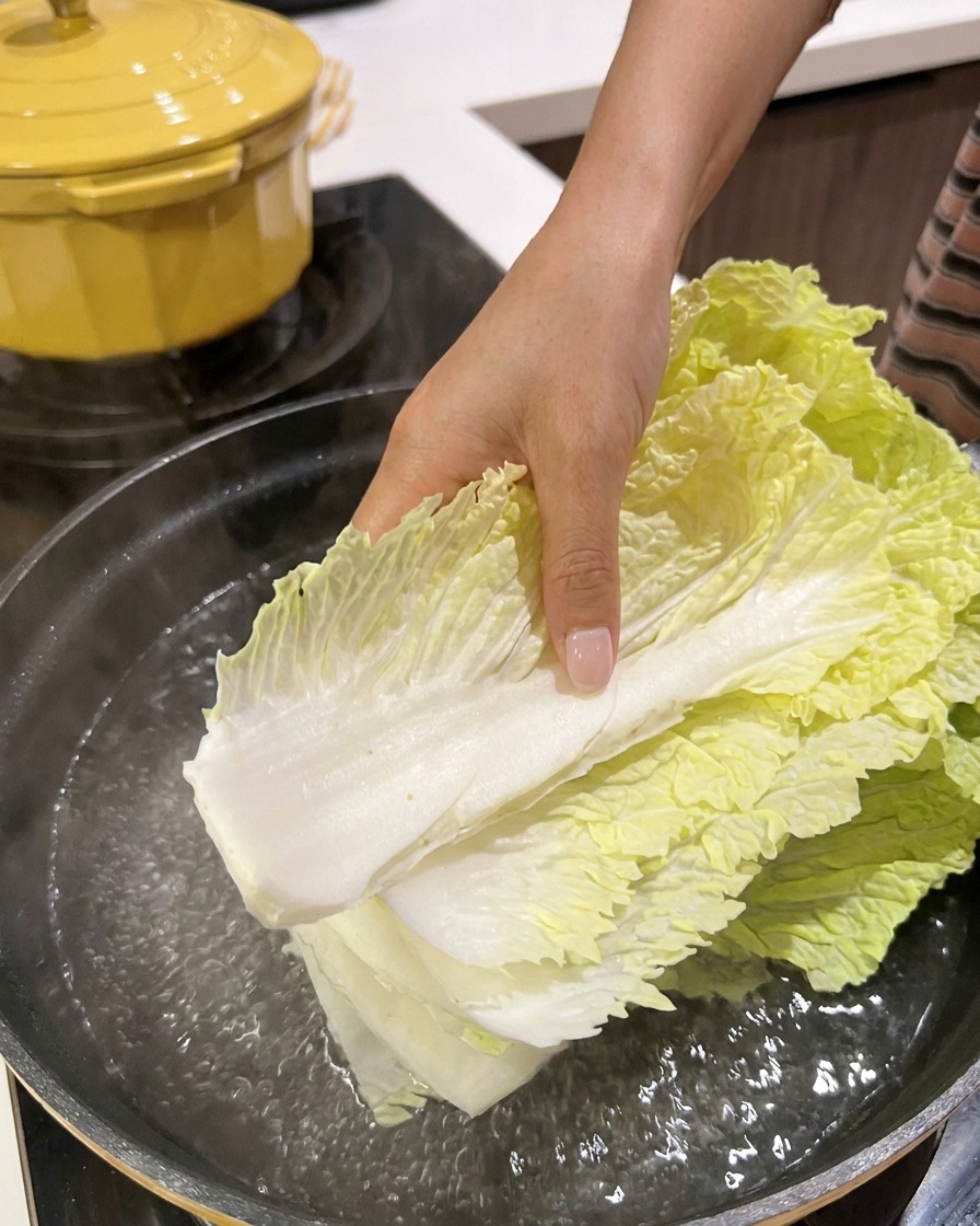 끓는 물이 담긴 냄비에 신선한 배추 잎을 넣는 모습