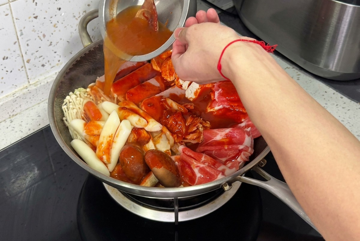 찌개 냄비에 물을 채우고 유리 뚜껑을 덮어 끓일 준비를 하는 모습.