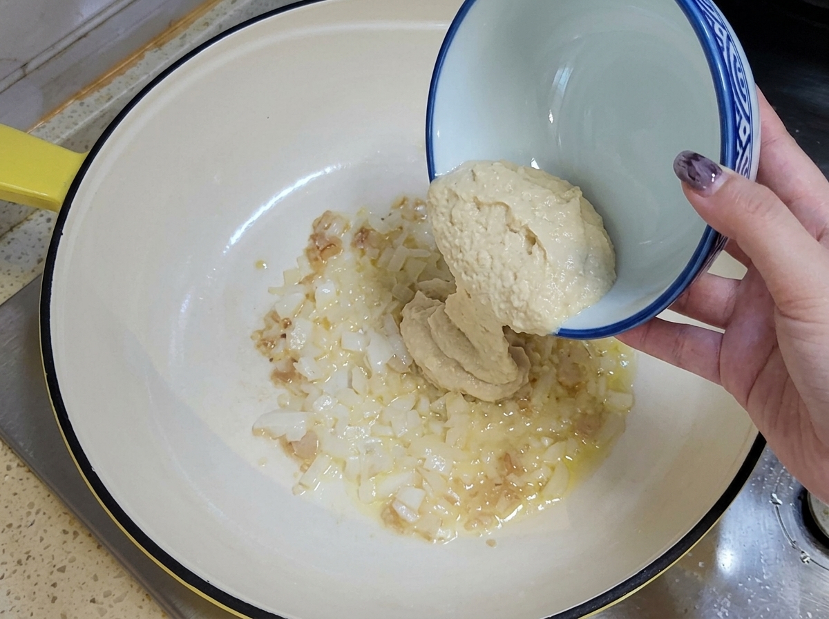 기름을 두른 팬에 다진 마늘과 양파를 붓는 모습.