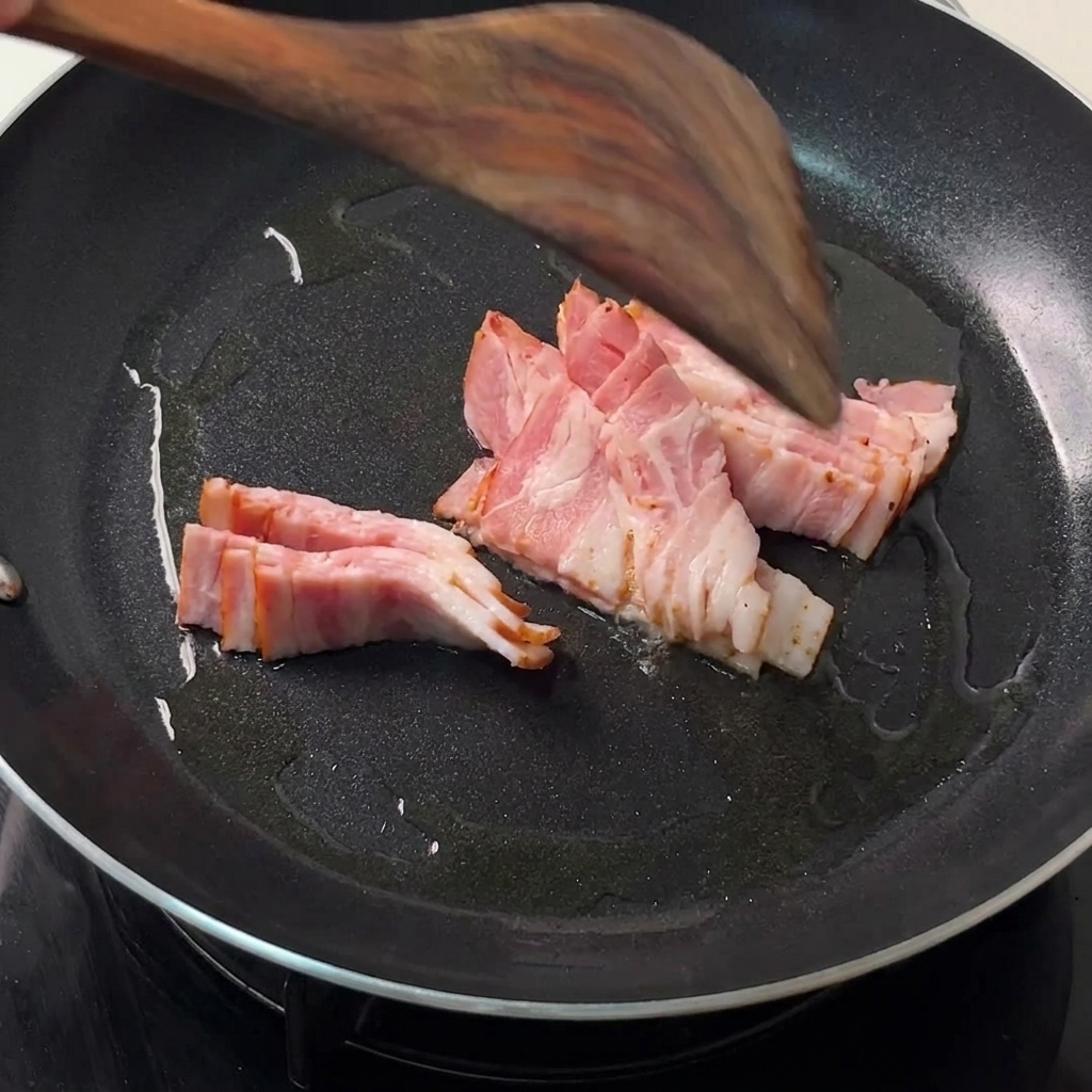 뜨거운 검은색 팬에서 나무 주걱으로 섞이며 구워지는 베이컨.