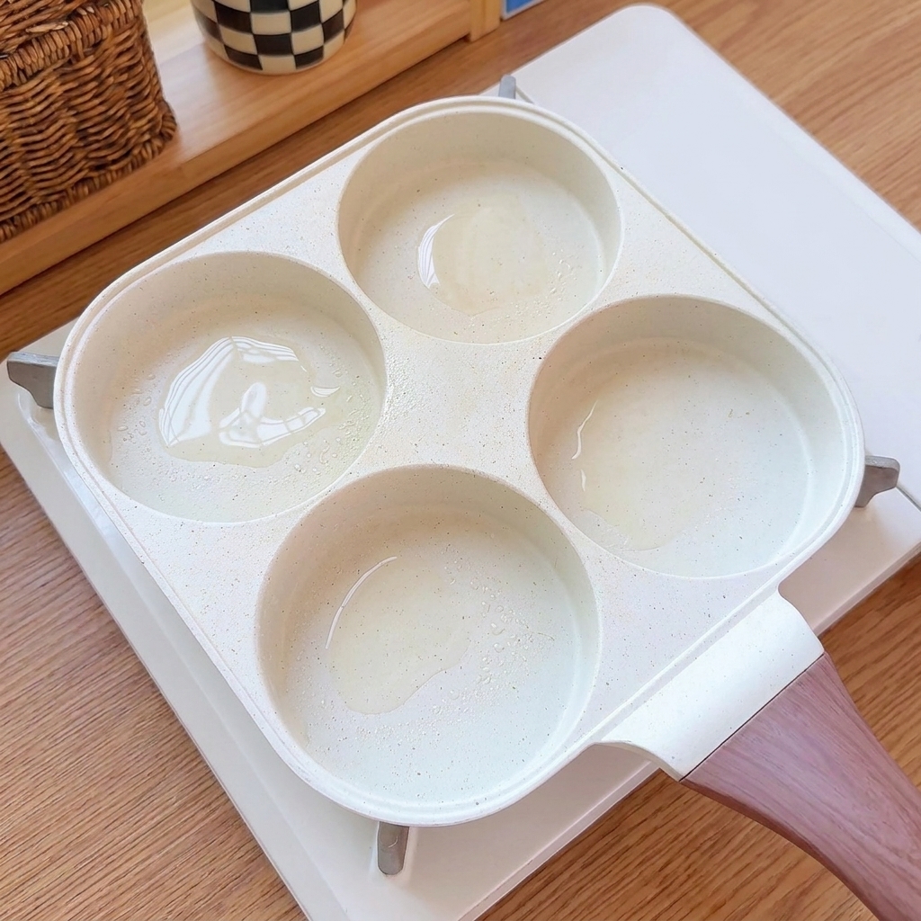 멀티 컵 프라이팬의 기름칠된 칸에 계란물이 부어지고 있는 모습.