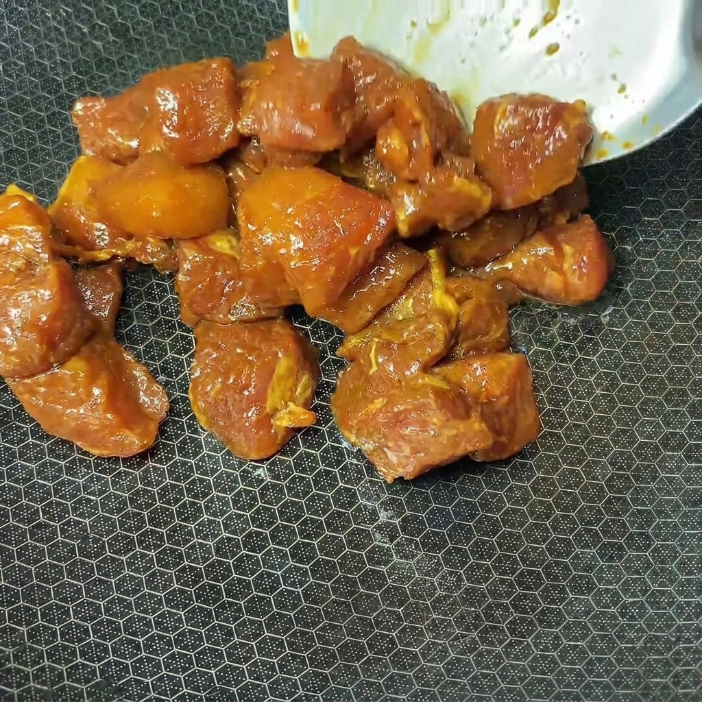조리를 위해 달궈진 웍에 양념된 돼지고기 큐브를 넣는 모습.