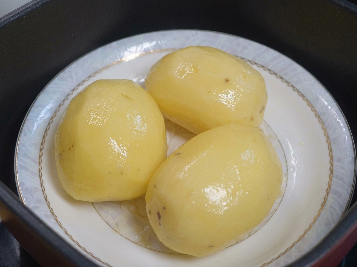 기름을 바를 준비가 된 접시 위의 찐 감자.