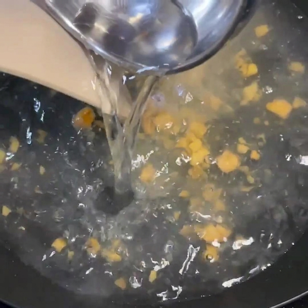 국자를 사용해 끓는 팬에 뜨거운 물을 붓고 조개를 넣는 모습.