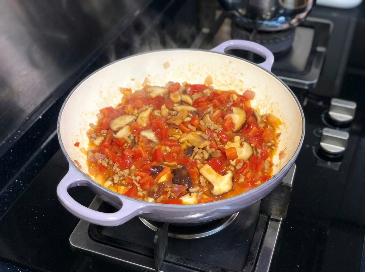 다진 토마토, 양파, 표고버섯이 팬에서 먹음직스럽게 끓고 있는 모습