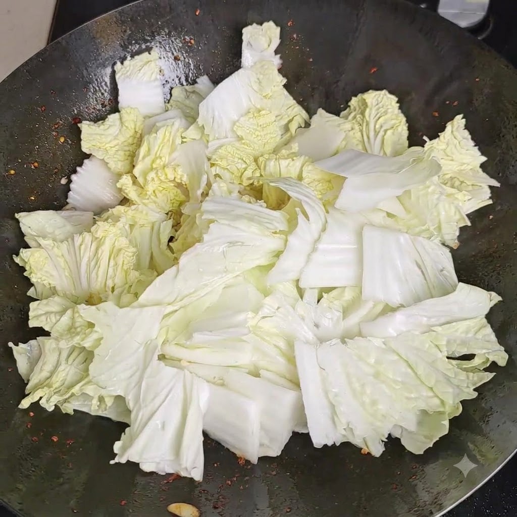 웍 안에 수북이 담긴 배추 위에 소금을 골고루 뿌리는 모습.
