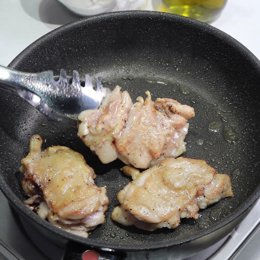 집게로 팬에서 구워진 닭다리살을 꺼내 도마 위에 올려 썰 준비를 하는 모습.