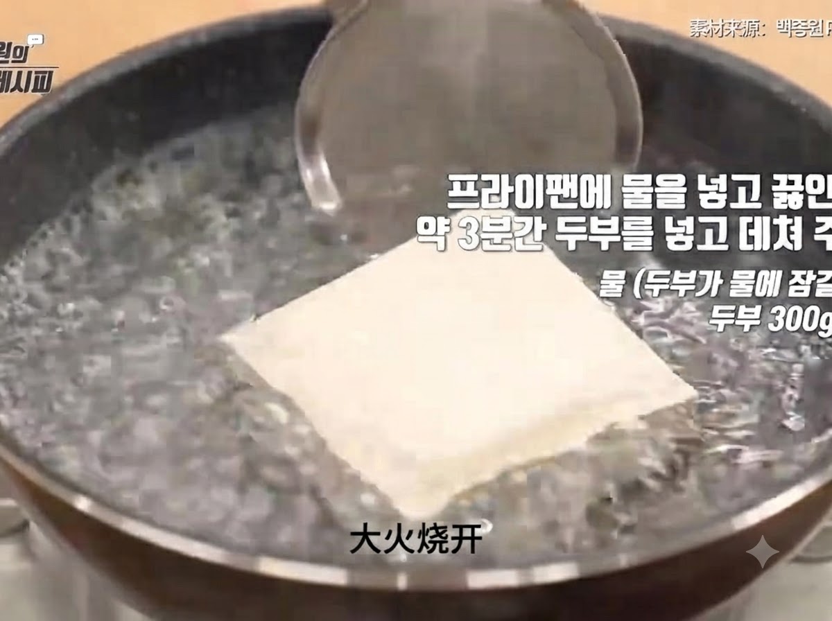 단단한 두부 한 모가 펄펄 끓는 냄비 물속에 잠겨 데쳐지는 과정.