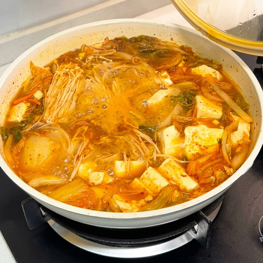 보글보글 끓는 찌개에 고추장 양념을 한 숟가락 넣는 모습.