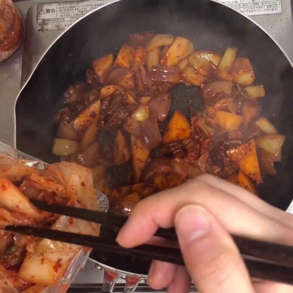 팬에 김치를 넣고 다른 재료들과 함께 섞는 모습.