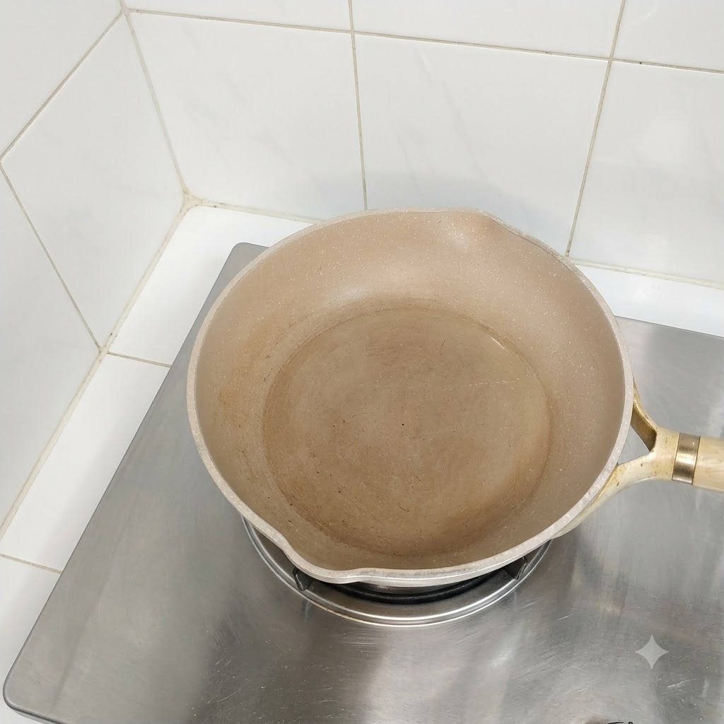 요리할 준비가 된, 기름이 둘러진 빈 팬이 스토브 버너 위에 놓여 있는 모습.