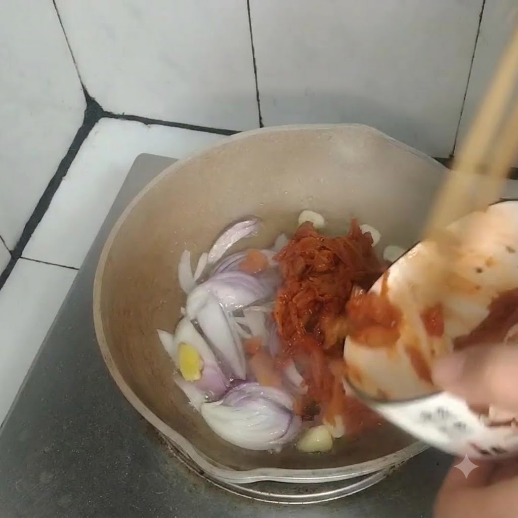 볶아진 양파, 마늘, 생강이 담긴 팬에 작은 그릇의 김치를 붓고 있는 모습.