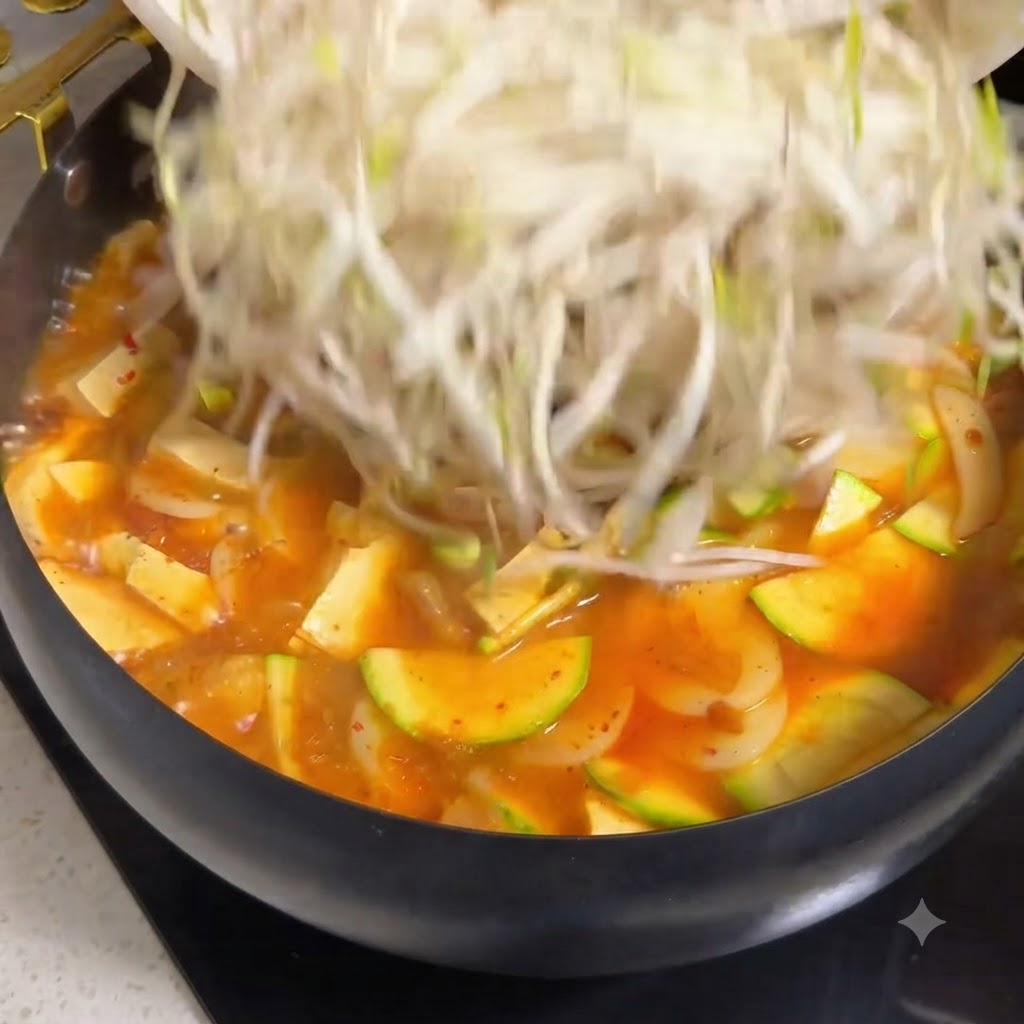 밥 돔 주변의 토마토 소고기 스튜 위에 모짜렐라 치즈가 뿌려지고 있는 모습.