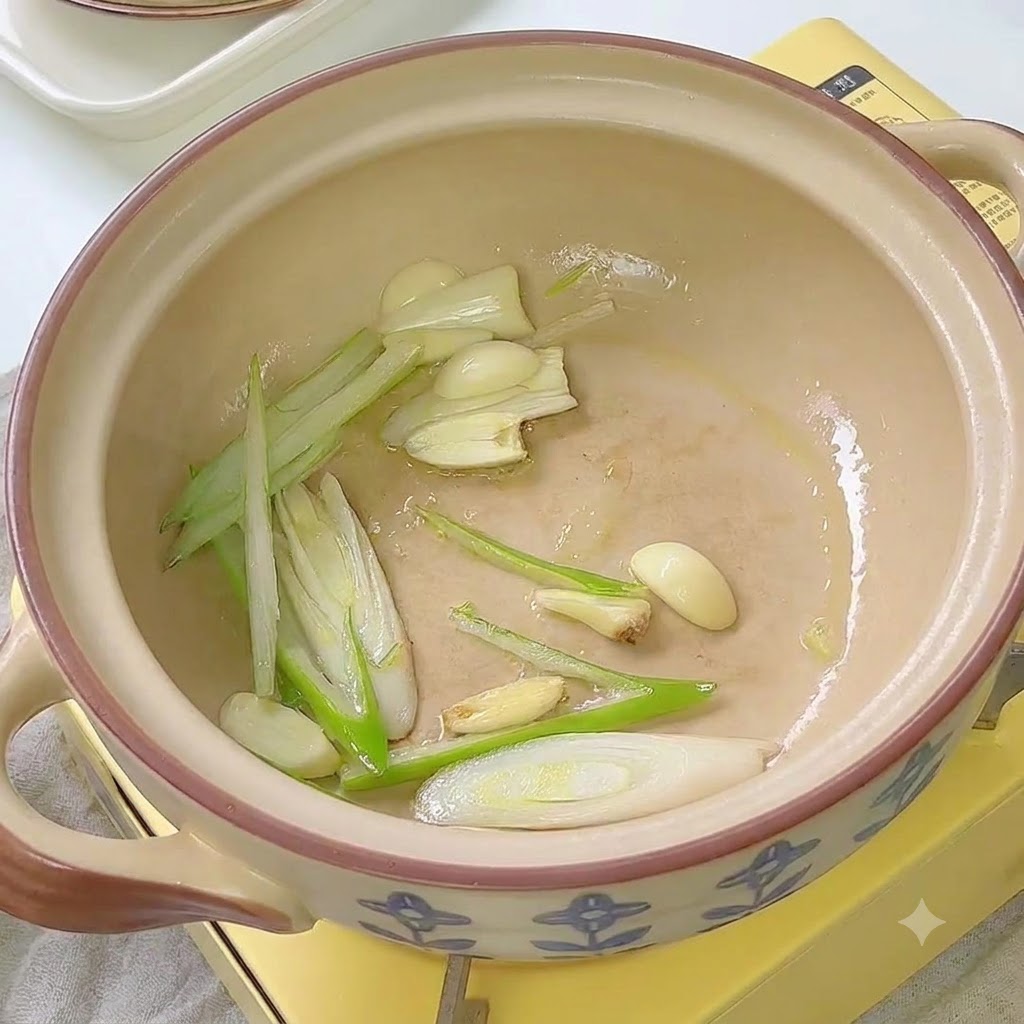 뚝배기 안에서 대파, 마늘과 함께 김치가 볶아지고 있습니다.