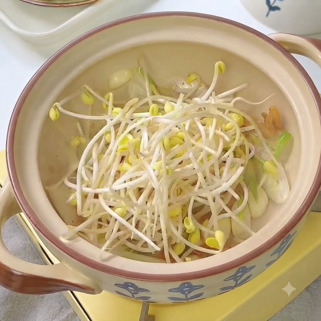 김치와 향신 채소가 담긴 냄비에 신선한 콩나물이 들어가 있습니다.