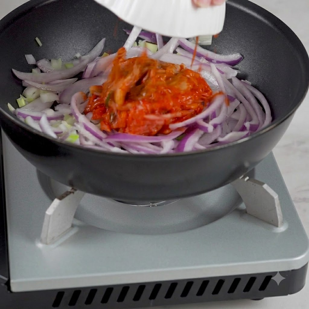 양파를 볶던 팬에 그릇에 담긴 김치를 넣는 모습