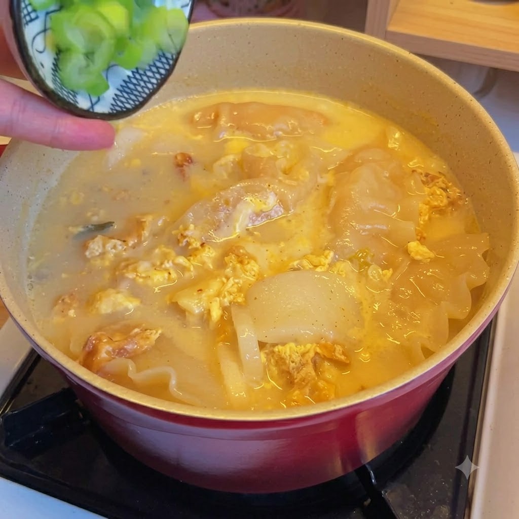 김치만두국 위에 다진 파가 뿌려지는 모습.