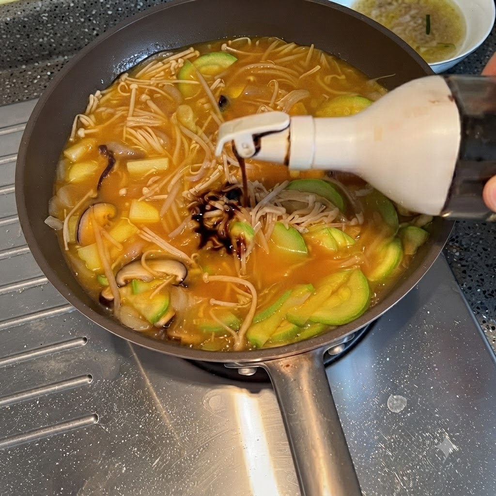 끓고 있는 채소 찌개에 병에서 간장이 짜 넣어지는 모습
