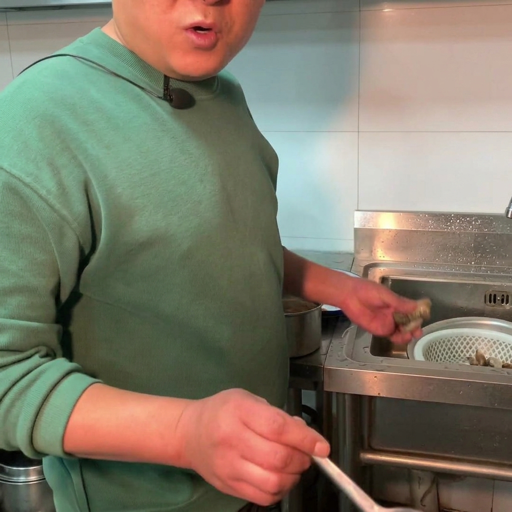 보글보글 끓는 된장찌개 냄비에 신선한 조개를 넣고 있는 모습.